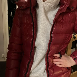 Fin Moncler-jacka - Vi köpte denna beg till vår dotter, för 2 år sen. Men den är endast använd 1 vinter. Vi har inget kvitto, men vi har aldrig tvivlat på att den inte skulle vara äkta.               Mycket varm och skön, i en härlig vinröd färg. Strl 2, som motsvarar 36 / S. Tjejen på bilden är 1,79 lång.