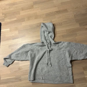 Grå hoodie - Mysig grå hoodie med luva och dragsko. Perfekt för kyliga dagar med sin avslappnade passform och ribbade muddar vid ärmslut och nederkant. Oanvänd (utan prislapp). 