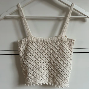 Beige stickad topp från ONLY - Säljer ett sött beiget stickat linne från ONLY. Toppen har ett fint hålmönster och smala axelband. Perfekt för varma dagar eller som ett lager under en kofta.