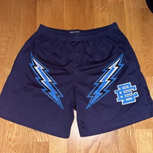 ERIC EMANUEL MESH SHORTS  - Snygga mörkblå shorts från Eric Emanuel med coolt blixtmotiv i blått och vitt. Perfekta för en sportig look. Tillverkade i New York. Skriv om ni har några frågor.