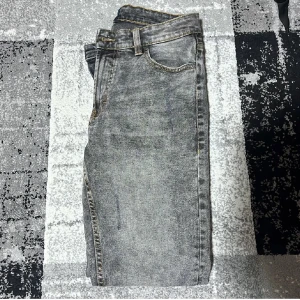 Grå jeans från Denim Project - Snygga grå jeans från Denim Project med en klassisk straight fit. De har en diskret tvättad look och är perfekta för en avslappnad stil. Jeansen har fem fickor och en knappgylf.