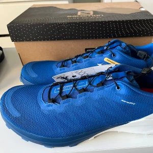 Blå Salomon Sense 4 Pro löparskor - Säljer ett par nya oanvända blå Salomon Sense 4 PRO, Trail Löparskor. Funkar väldigt bra om du gillar att springa mycket ute i skogen! 