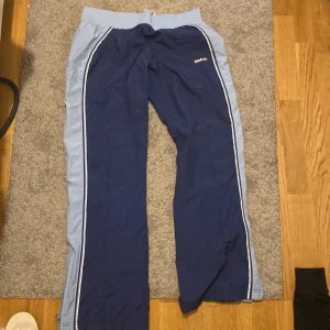 Blå träningsbyxor från Reebok - Snygga blå träningsbyxor från Reebok med ljusblå detaljer och dragkedjor vid bensluten. Det ena vita snöret är av som man kan se på bilden 🙏 Köpte second hand och har knappt använt dem själv 