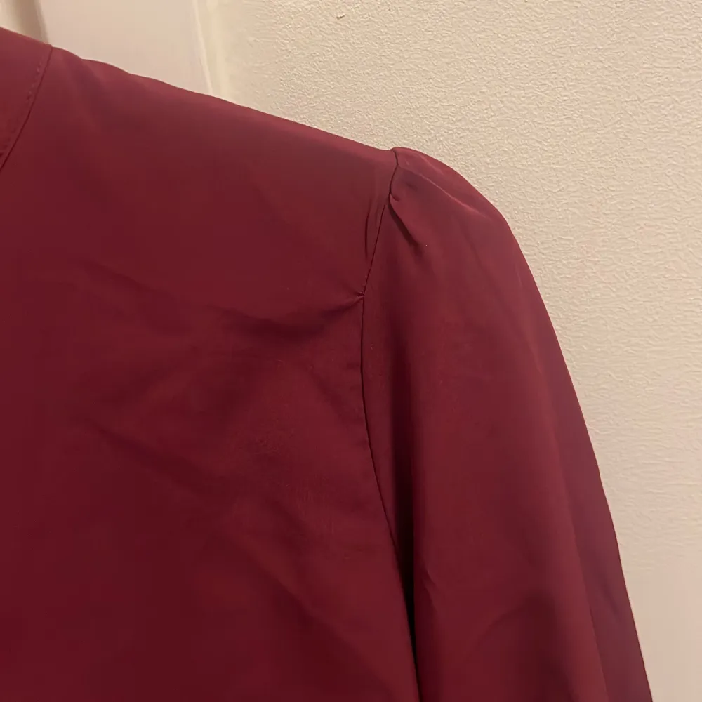 Söt blus med mininal, diskret puffärm. 5 knappar framtill som går att knäppa upp. Resår i armarna nedtill. Oanvänd. . Puserot.