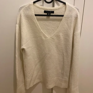 Vit stickad tröja från Amisu - Mysig vit stickad tröja från Amisu med v-ringning. Perfekt för kyliga dagar med sin mjuka och bekväma passform. Långärmad design som passar bra till både jeans och kjol.