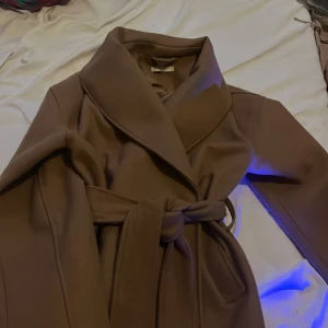 Beige kappa från Gina Tricot - Snygg beige kappa från Gina Tricot i storlek S. Den har en elegant knytning i midjan och långa ärmar. Perfekt för höst och vår. Har använt kappan ungefär 5 gånger, men köpte en annan i mindre storlek så har ingen användning av denna❣️köpte den för 800kr men säljer den för 650