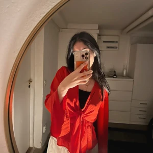 Röd omlottopp från Gina Tricot - Snygg röd omlottopp från Gina Tricot med långa ärmar och knytning i midjan. Perfekt för att ge en färgklick till din outfit. Toppen har en v-ringad design som ger en elegant touch.