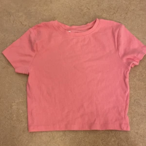 Rosa ribbad t-shirt - Säljer en söt rosa ribbad t-shirt med korta ärmar. Perfekt för en avslappnad stil.
