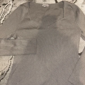 Grå tröja - Snygg grå tröja med långärmad design och v-ringad hals. Perfekt för en stilren look. Helt okej skick.