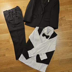 Svart kostym med väst och fluga - Elegant svart kostym med kavaj, byxor, väst och vit skjorta med svart fluga. Använd en gång
