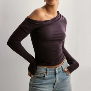 Svart offshoulder topp - Snygg mörkbrun/lila offshoulder topp med lång ärm och tight passform. Perfekt för en stilren look med en twist. Toppen har en elegant asymmetrisk design. Storlek XXS men i vädligt stretchigt material så passar en XS. Ny med prislapp kvar🤎