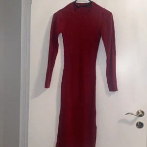 Röd ribbad långklänning - Snygg röd ribbad långklänning med långärmad design. Perfekt för kyligare dagar med sin stilrena och figurnära passform.