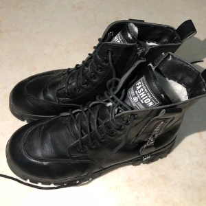 Svarta boots med snörning och dragkedja - ❗️TAR ENDAST EMOT SWISH, skriv t mig vid köp ❗️ Snygga svarta boots i skinn med både snörning och dragkedja för enkel på- och avtagning. De har en robust sula och är fodrade med vitt material för extra värme. Använda några gånger.