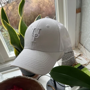 Vit keps från Urban Pioneers - Snygg vit keps från Urban Pioneers med broderad logotyp framtill. Kepsen har en klassisk design med justerbar passform och ventilerande hål för extra komfort. Perfekt för en stilren look.