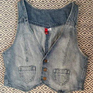 Jeansväst med knappar - Snygg jeansväst från Lindex, köpt secondhand. Storlek 40/42. !KÖP ENDAST VIA POSTNORD!