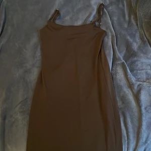 Brun axelbandslös klänning - Snygg brun klänning med axelband och en elegant, enkel design. Perfekt för en stilren look.