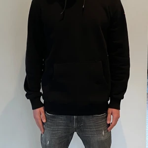 Bastille Rive Droite - Snygg svart hoodie med en stor färgglad tryck på ryggen. Tröjan har en klassisk känguruficka och justerbar huva med dragsko. Perfekt för en avslappnad stil. Tröjan är inte använd mycket och är i storlek L