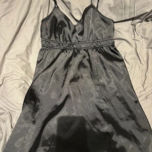 Svart satin klänning - Elegant svart klänning i satin med smala axelband och v-ringning. Perfekt för en stilren look. Gammal kollektion ifrån Gina tricot men är använd ca 10 gånger och är som ny 🩷🩷🩷🩷