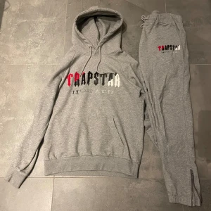 Trapstar dress - Säljer nu min trapstar dress. Hoodien har en stor logotyp i rött, svart och vitt på bröstet. Byxorna har en mindre logotyp på ena benet och resår i midjan för bekväm passform.