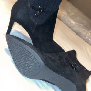 Svarta boots från Michael Kors - Snygga svarta boots i mocka från Michael Kors med ribbad detalj upptill och en liten spänne. Storlek 40 med klack på 7cm!