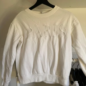 Vit tröja med brodering - Vit tröja med broderingen ”Paris”. Små defekter på broderingen men inget som riktigt syns. Använd ett fåtal gånger.