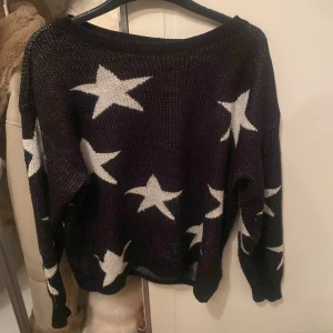 Svart stickad tröja med stjärnor - Säljer en svart stickad tröja med vita stjärnor. Tröjan har långa ärmar och en avslappnad passform. Perfekt för kyliga dagar och ger en cool look med sitt stjärnmönster.