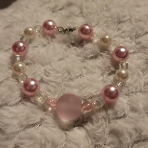 Pärlarmband med rosa och vita pärlor - Charmigt armband med stora rosa och vita pärlor, kombinerat med mindre genomskinliga pärlor. Perfekt för att ge en söt och elegant touch till din outfit.