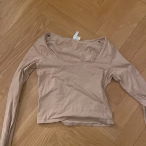 Beige långärmad topp från H&M Divided - Säljer en stilren beige långärmad topp från H&M Divided. Perfekt för en enkel och avslappnad look. Toppen har en rund halsringning och är tillverkad i ett mjukt material.