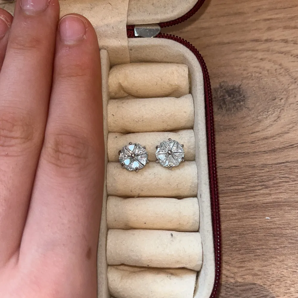 Snygga silverfärgade örhängen med glittrande stenar. Perfekta för att ge en elegant touch till din outfit. Kommer i en praktisk förvaringsask.. Asusteet.