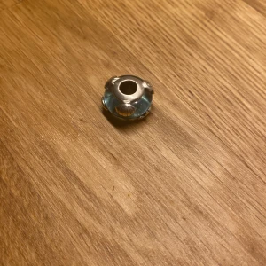 Pandora berlock  - En Pandora berlock i ljusblå färg med snäck dekorationer. 