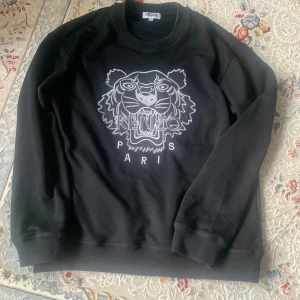 Svart sweatshirt från Kenzo - Snygg svart sweatshirt från Kenzo med ett stort tigertryck. Den är relativt ny och skick på 9/10. Nypris går för 1600 ish.
