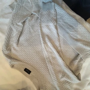 Grå stickad tröja från Vila - Säljer en stilren grå stickad tröja från Vila. Tröjan har ett diskret mönster och ribbade muddar vid ärmslut och nederkant. Perfekt för kyligare dagar smuts vit.