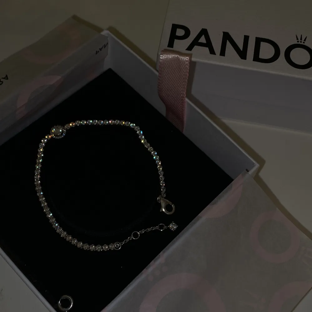 Elegant silverarmband från Pandora med gnistrande stenar. Armbandet har en justerbar kedja och ett säkert lås. Perfekt för att lägga till en touch av glamour till din stil. Kvittot finns kvar och lådan också💕. Asusteet.