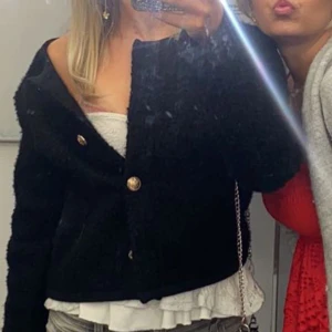 Svart jacka från Gina Tricot - Snygg svart jacka från Gina Tricot med guldknappar. Jackan har en texturerad yta och rund halsringning. Perfekt för att ge en stilren look.