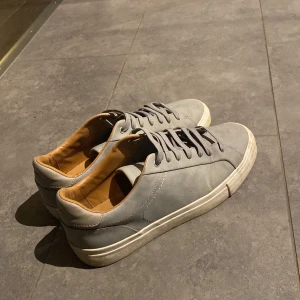 Grå sneakers med snörning - Snygga grå sneakers med snörning och en stilren design. Skorna har en ljus sula och en bekväm insida i beige. Perfekta för en avslappnad stil.