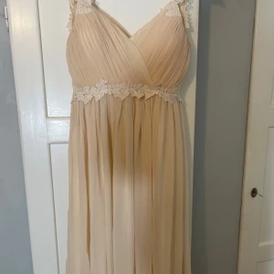 Champagnefärgad långklänning med spets - Champagnefärgad långklänning med spets. Den är uppsydd någon centimeter hos skräddare, så inga lösa trådar. Använd endast en gång. Köpt från bubbleroom, nypris 1700kr