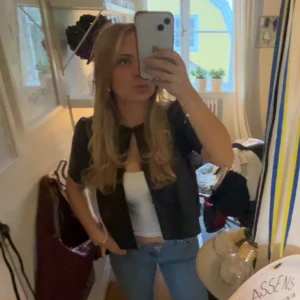 Svart kortärmad blus - Snygg svart kortärmad topp i skinnliknade material. Man kan ha den både stängd och öppen. Köpt på Gina Tricot för några månader sedan men endast använd en gång💕☺️Skriv för fler bilder!💗💗