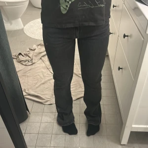 Svarta jeans från Gina Tricot - Snygga svarta jeans från Gina Tricot med en klassisk design. De har en dragkedja och knapp framtill och är perfekta för en stilren look. Midjemått rakt över är 36cm. Innerbenslängden är 76cm. Köpta föe ca 500kr