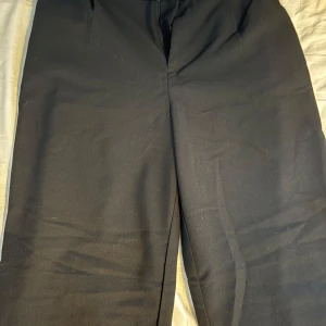 Svarta kostymbyxor - Snygga svarta kostymbyxor med en klassisk design. Perfekta för en stilren look. Byxorna har en rak passform och är tillverkade i ett bekvämt material.