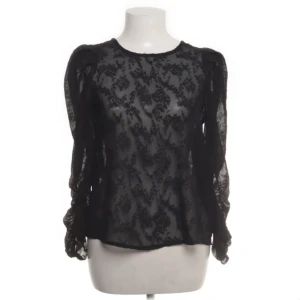 Svart spetsblus från MNG - Elegant svart spetsblus från MNG med långärmad design och ett fint mönster. Blusen har en liten öppning i ryggen och passar bra till både jeans och kjol, den är lite nopprig annars inga synliga defekter!