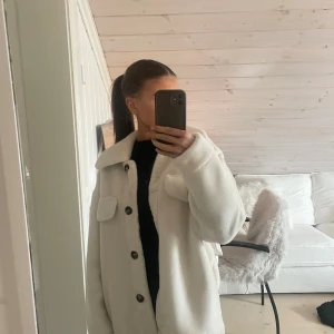 Vit teddyjacka från Livelo - Säljer en supermjuk vit teddyjacka från Livelo i storlek 38. Jackan har en klassisk krage och knäpps med knappar framtill. Perfekt för att hålla sig varm och stilren under kyliga dagar. 🐻✨