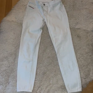 Ljusblå jeans från Diesel st.26 - Snygga  jeans från Diesel med låg midja och smal passform. De har en klassisk femficksdesign och en diskret logga på fickan. Perfekta för en stilren look.