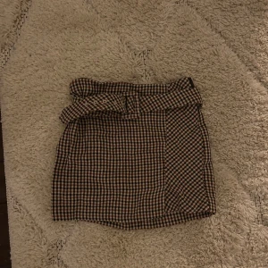 Rutig kjol med knytband - Snygg rutig kjol med knytband i midjan. Perfekt för en stilren look. Kjolen har en klassisk design med ett modernt twist.