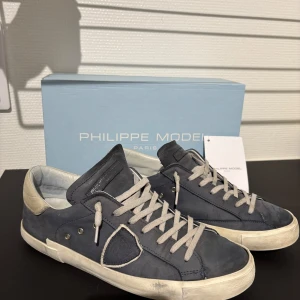 Blå sneakers från Philippe Model - Säljer dessa Philippe Models då jag växt ut dom. Det är storlek 42 men skulle säga att de sitter lite större. De är i okej skick (sulan drar ner lite) och nypris (som du ser på boxen) är 340 €. Allt OG fås med som taggen och box m.m. Tveka inte att höra av er, pris kan diskuteras. 