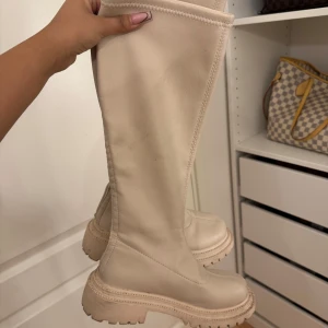 krämvita stövlar  - Snygga stövlar som är höga och har en enkel design utan snörning eller dragkedja.