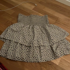 Prickig kjol med volang - Charmig kortkjol i vitt med svarta prickar och volangdetaljer. Perfekt för en somrig look. Den elastiska midjan ger en bekväm passform.