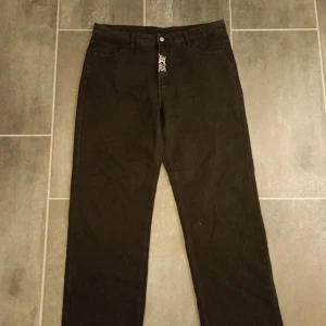 Svarta jeans med broderi - Coola svarta jeans med unikt vitt broderi på benet och bakfickan. De har en rak passform och är perfekta för en edgy stil. Broderiet ger en extra touch av personlighet.