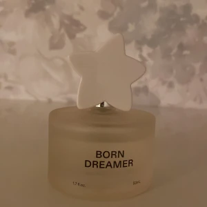 Born Dreamer av Charli D’Amelio - Born Dreamer i en stilren flaska med en vit stjärnformad kork. Flaskan rymmer 50 ml och har en frostad yta som ger ett elegant intryck. Perfekt för den som vill ha en unik och drömsk doftupplevelse.