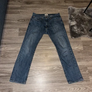 Blå jeans från Grant - Säljer ett par klassiska blå jeans från Grant i regular fit. De har en traditionell femficksdesign och är perfekta för en avslappnad stil. Midjan är midwaist och byxorna har en rak passform.