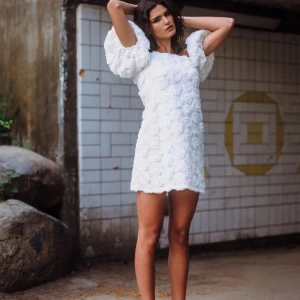 Ida Sjöstedt klänning June  - Tryck inte på köp nu utan dialog med mig.                         Säljer en vit klänning med rosdetaljer över hela tyget. Klänningen har en offshoulder-design med puffiga ärmar som ger en romantisk känsla. Perfekt för studenten.  Helt ny och oanvänd med lapp kvar på klänningen. 